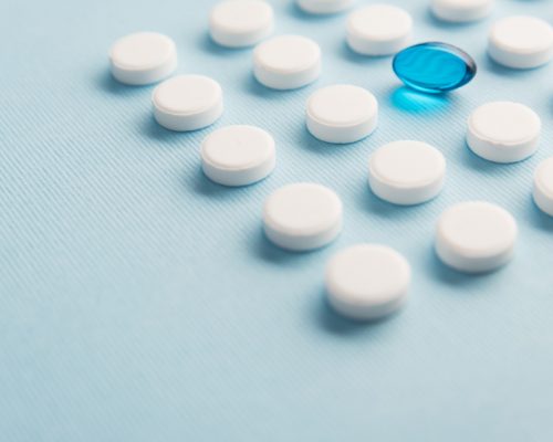 close-up-one-capsule-surrounded-by-white-tablets